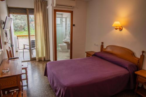 - une chambre avec un lit violet et une salle de bains dans l'établissement Hotel Herasu, à Peñíscola