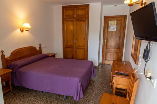 - une chambre avec un lit violet et une télévision à écran plat dans l'établissement Hotel Herasu, à Peñíscola