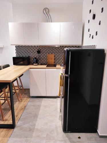 um frigorífico preto numa cozinha com uma mesa em Mirror Apartments em Oświęcim