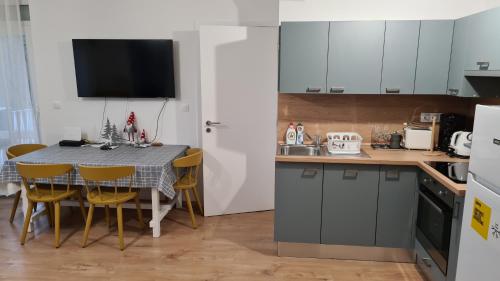 een keuken met een tafel en stoelen en een keuken met witte kasten bij Pelso apartman in Keszthely