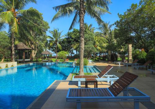 - une piscine avec 2 chaises et une table à côté d'un palmier dans l'établissement The Jayakarta Suites Komodo Flores, à Labuan Bajo