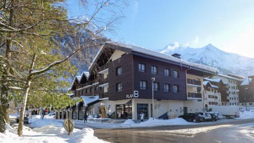 um grande edifício na neve com montanhas ao fundo em Plan B Hotel - Living Chamonix em Chamonix-Mont-Blanc