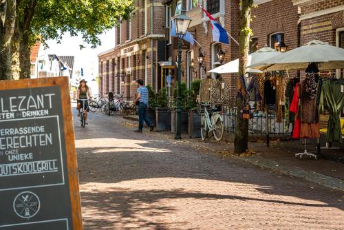 a man walking a bike down a street with a sign at Loods Hotel Vlieland in Oost-Vlieland