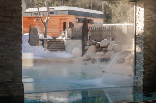 a pool of water with a waterfall in a yard at Croce Bianca Leisure & Spa Hotel in Canazei