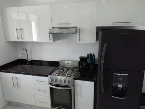 a kitchen with a stove and a black refrigerator at Venecia 262 in Puerto Vallarta