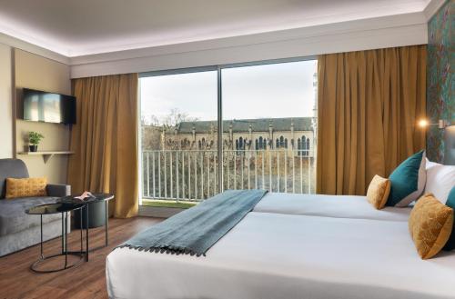 een hotelkamer met een groot bed en een groot raam bij Hôtel Charlemagne by Happyculture in Lyon