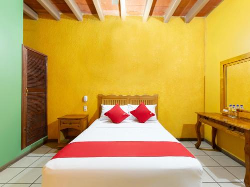 een slaapkamer met een bed met rode kussens en een bureau bij Hotel Posada San Rafael in Oaxaca City