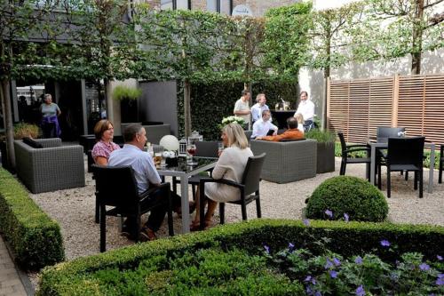 un gruppo di persone seduti a un tavolo in un giardino di Flanders Hotel a Bruges