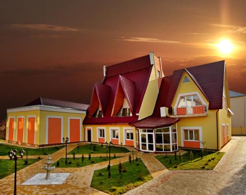 a house with a red roof with a sunset in the background at Гранд Алексік in Truskavets