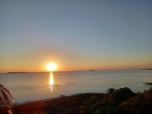 een zonsondergang boven het water met zonsondergang bij Monoambiente en Colonia in Colonia del Sacramento