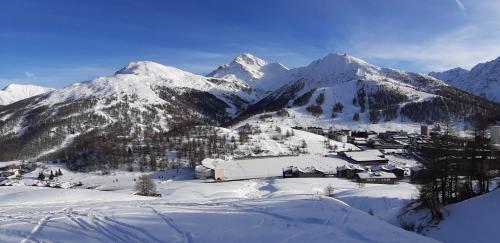 a snow covered mountain with a village in the foreground at Hotel Lago Losetta in Sestriere