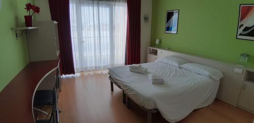 a bedroom with a white bed in a green room at Hotel Lago Losetta in Sestriere