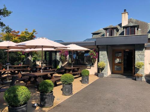 un restaurant avec des tables en bois et des parasols dans l'établissement The Mary Mount Hotel, à Keswick