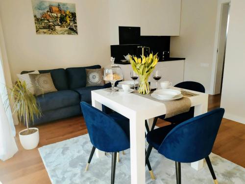 a living room with a white table and blue chairs at Apartamenty RÓŻANA 2 in Nałęczów