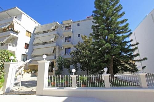 Un edificio bianco con una recinzione e un albero di Natale di Star Hotel Saranda a Sarandë