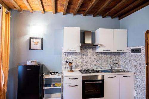 a kitchen with white cabinets and a black refrigerator at Residenza Roma in Pistoia