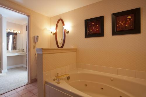 ein Bad mit einer Badewanne und einem Spiegel in der Unterkunft The Fredericton Inn in Fredericton