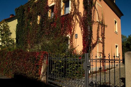 un edificio ricoperto di edera con una recinzione di fronte ad esso di Franks kleines Bauernhaus in Dresden a Dresda