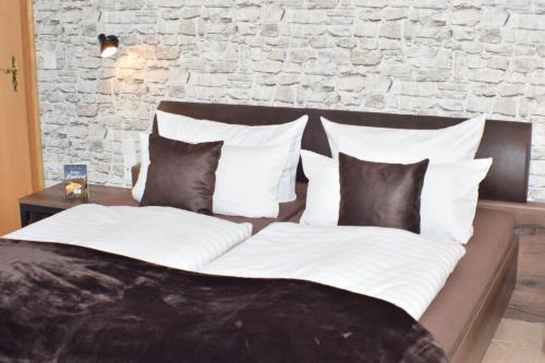 a bed with black and white pillows and a brick wall at Bachmeier's Gasthaus Traube Niederfell in Niederfell