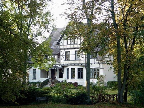 una casa blanca con árboles delante de ella en Gutshaus Kubbelkow, en Bergen auf Rügen