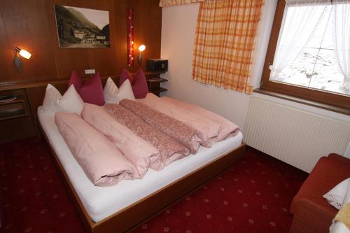 a bedroom with a bed with pink pillows at Haus Alpenglühn in Längenfeld