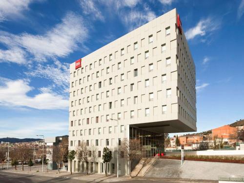 un edificio blanco con un letrero rojo. en Ibis Barcelona Santa Coloma, en Santa Coloma