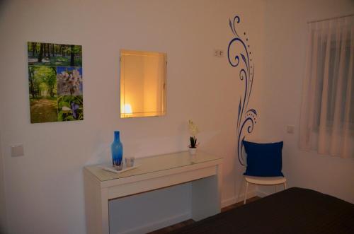 a room with a table and a blue vase and a chair at Cazenn Nazaré - Apartment Z in Nazaré