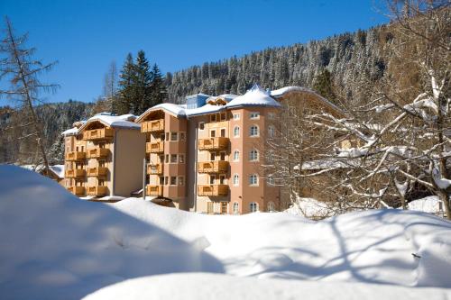 ein schneebedecktes Gebäude vor einem Berg in der Unterkunft Hotel Chalet Del Brenta in Madonna di Campiglio