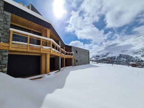 un edificio en la nieve con montañas en el fondo en Chalet Le Granitic, en Les Menuires