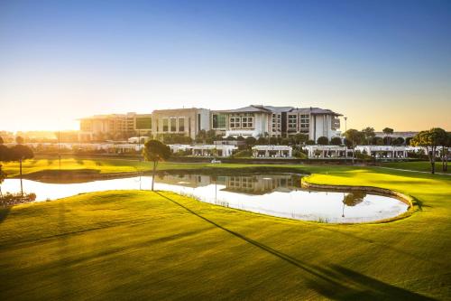 un parcours de golf avec un étang en face d'un bâtiment dans l'établissement Regnum Carya, à Belek