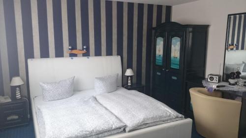 een slaapkamer met een wit bed en een zwarte kast bij Landhotel Ostseetraum & Fewo in Warnemünde