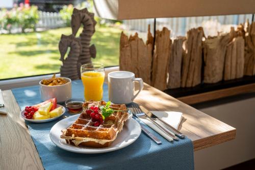 een ontbijt met wafels, fruit en jus d'orange op een tafel bij Das Frühstückshotel Büsum in Büsum