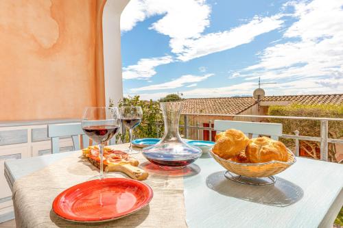 una mesa con dos copas de vino y una cesta de pan en Shanti House Olbia, en Olbia