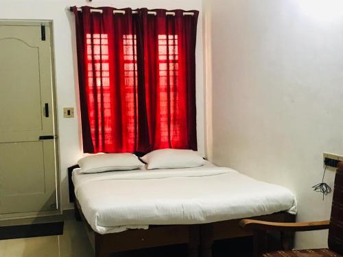 a bed in a room with a red window at Ice Berg Deluxe Lodge in Kushālnagar