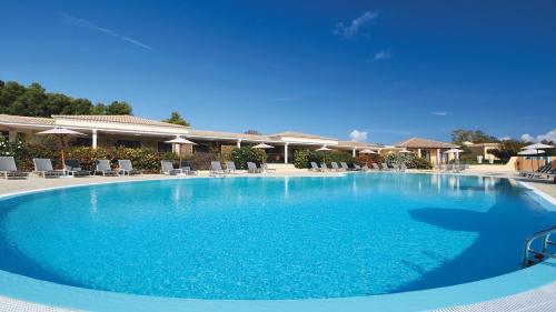 una grande piscina con acqua blu in un resort di SECRET VILLAGE Budoni a Budoni