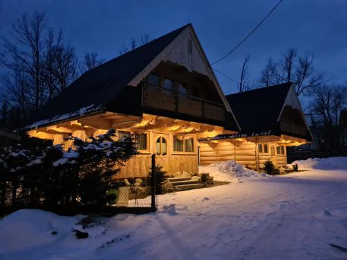 una cabaña de madera en la nieve por la noche en Domki u Magdy, en Zakopane