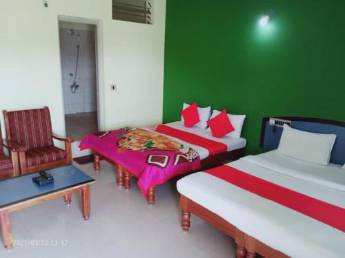 a bedroom with two beds and a green wall at Ice Berg Deluxe Lodge in Kushālnagar