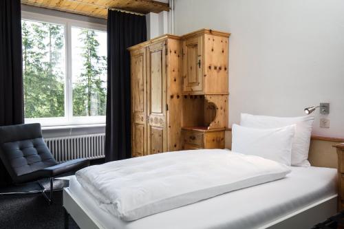 una camera con un letto e una sedia e una finestra di Kurhaus Lenzerheide a Lenzerheide