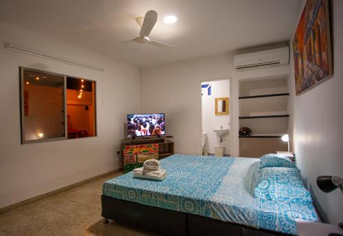 a bedroom with a bed and a flat screen tv at Hostal El Bando in Cartagena de Indias