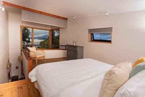 1 dormitorio con cama blanca y balcón en Cala Melí, en Puerto Varas