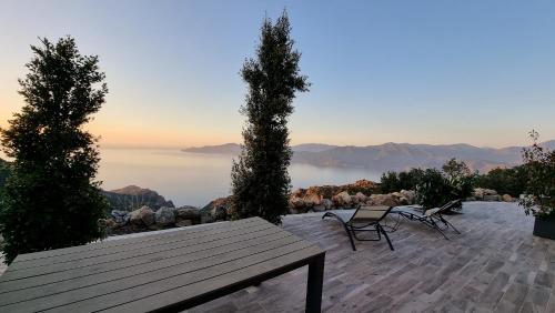 uma mesa de madeira e cadeiras num pátio com vista em Résidence Le Bella Vista em Piana