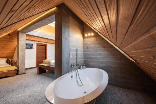 a bathroom with a white tub and a bedroom at Stara Pravda Villas in Bukovel