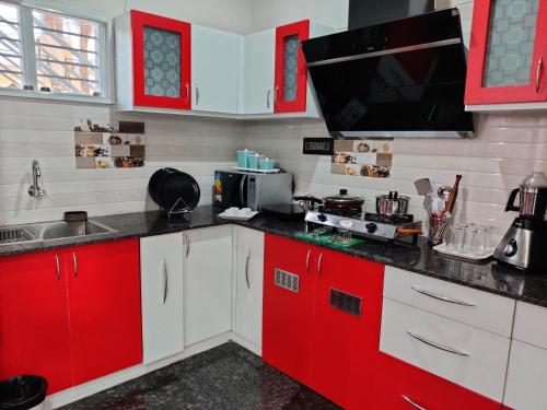 una cucina con armadi rossi e bianchi e forno a microonde di Royal Wings Apartments a Mysore