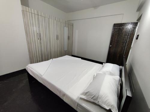 una camera con letto bianco e testiera in legno di Royal Wings Apartments a Mysore