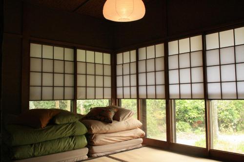 Zimmer mit Fenstern und einem Haufen Decken in der Unterkunft 88 House Hiroshima in Hiroshima