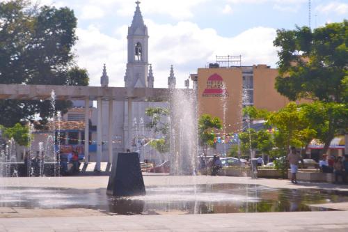 une fontaine au milieu d'une ville avec une tour d'horloge dans l'établissement Hotel Plaza Independencia, à Villahermosa