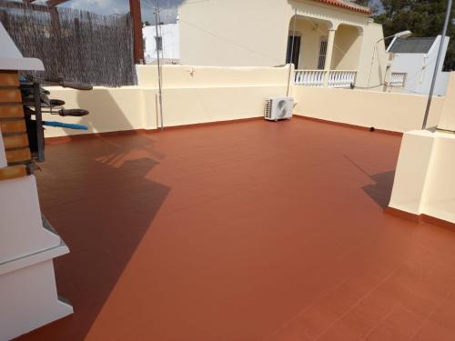 un balcone con pavimento rosso e parete bianca. di Maré Beach a Monte Gordo