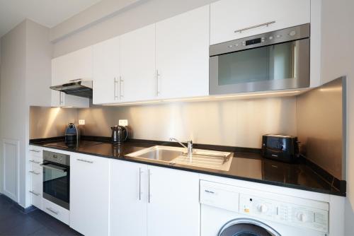 een witte keuken met een wastafel en een magnetron bij Thon Hotel Residence Parnasse Aparthotel in Brussel