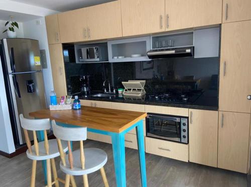 une cuisine avec une table en bois et deux tabourets dans l'établissement Apto 307 Metroloft Armenia, à Armenia