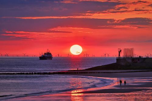 弗利辛恩Westerschelde B&B的海滩上的日落,在海洋中划船